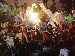 Protestors burning the Israeli flag in front of the embassy in London